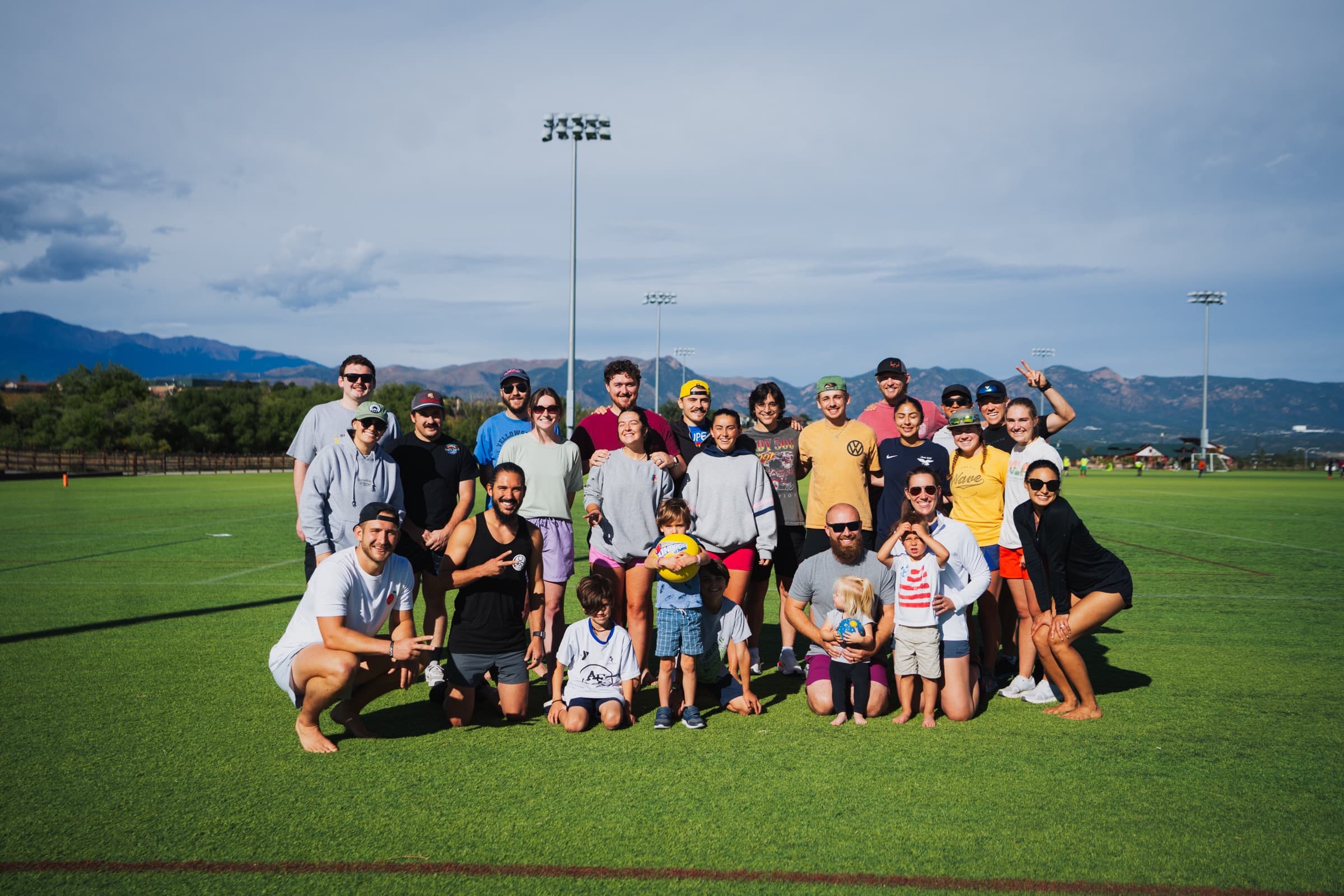 The Elevate community gathered on a field after kickball, with the Front Range behind them