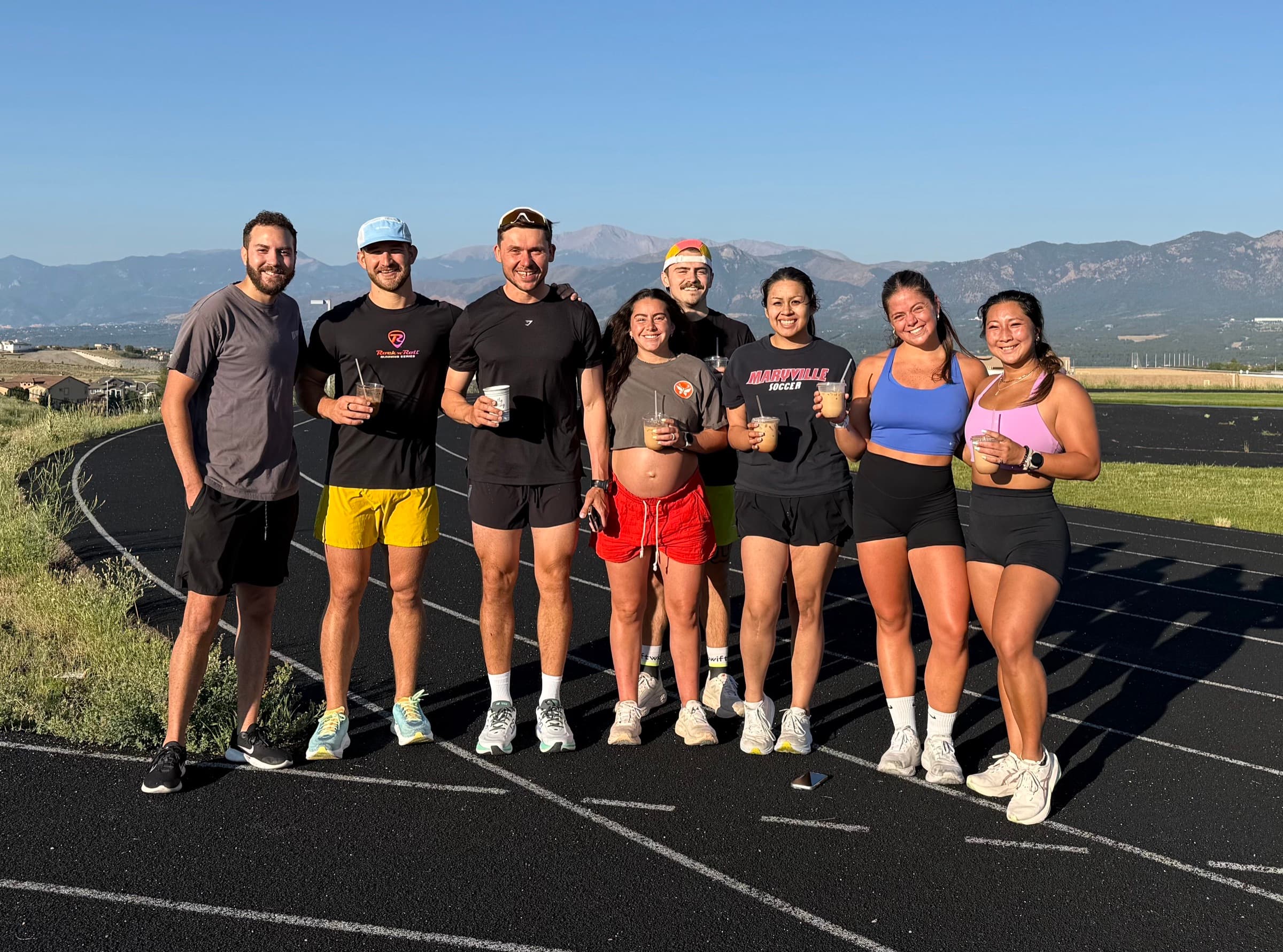 Elevate run club on the track with iced coffees and Pikes Peak in the background