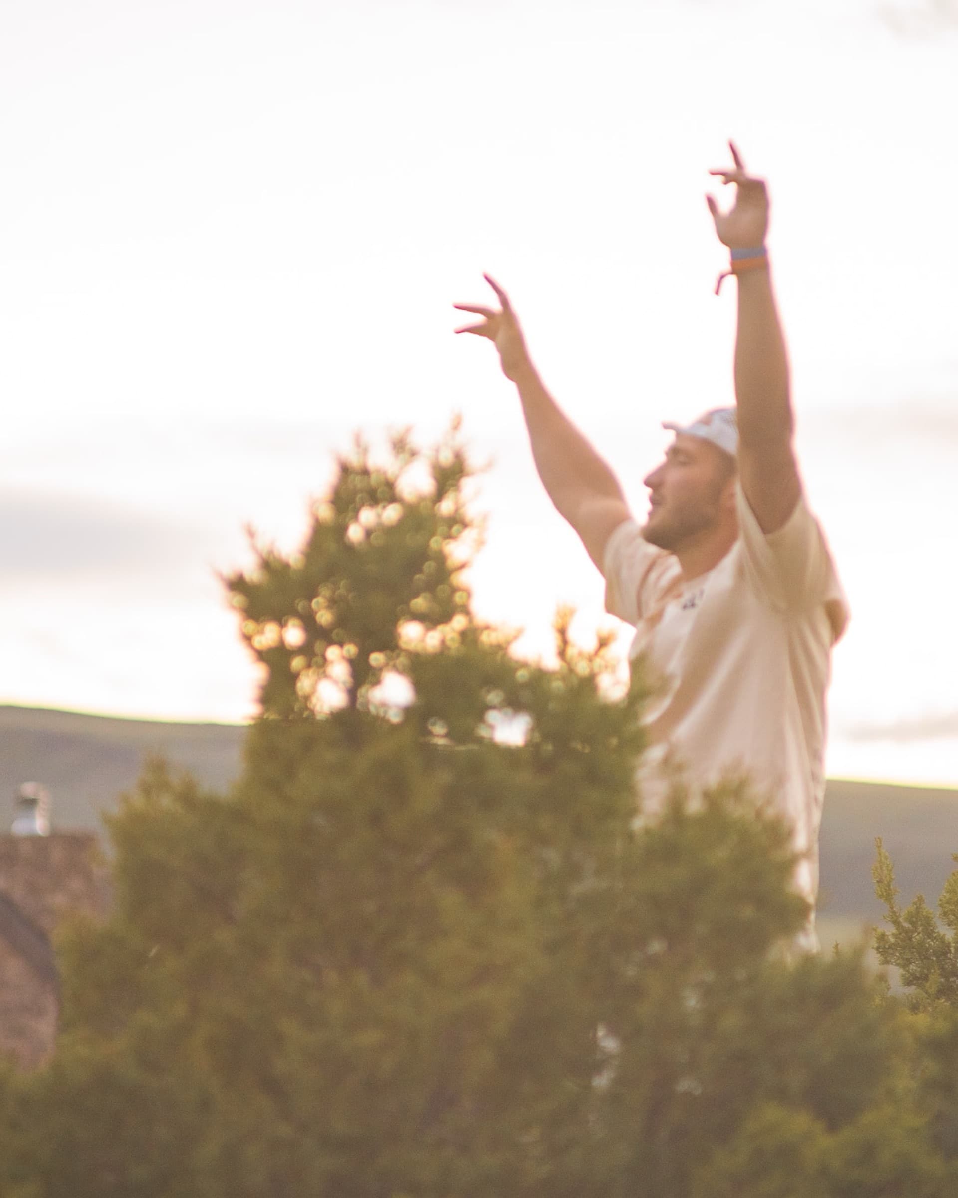 A member worshipping with hands raised at golden hour